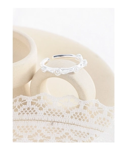 Detailed view of silver wrinkled texture ring with delicate pearls on beige ceramic base