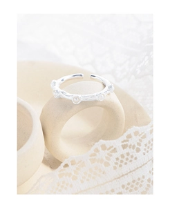 Close-up of silver ring with crinkled texture and pearls on lace background