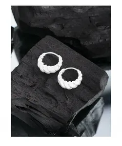Vue détaillée des boucles d'oreilles créoles torsadées argentées sur charbon noir