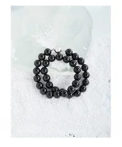 Gros plan sur les perles en onyx noir et le fermoir argenté du bracelet double rang