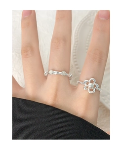Detailed view of silver flower pearl ring and textured bead ring on finger