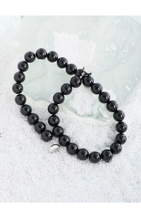 Détail de deux bracelets en agate noire avec fermoirs magnétiques sur des cristaux blancs