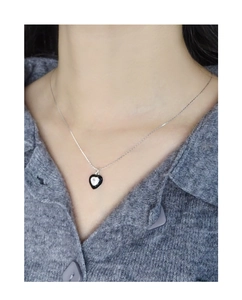 Detail of silver S925 heart necklace with black enamel drip design on grey sweater