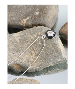 Detailed shot of S925 silver heart necklace with black enamel and zircon on a stone