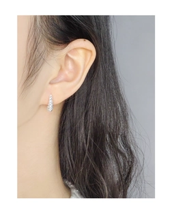 Détail des boucles d'oreilles créoles torsadées en argent S925 portées par un mannequin