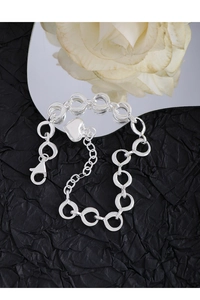 Polished silver heart pendant bracelet on a reflective mirror with white roses