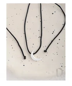 Macro view of S925 sterling silver moon pendant with black cord on a ceramic plate