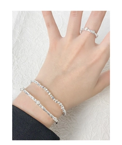 Detail of silver S925 bracelet with wrinkled texture and pearls on white fabric