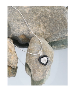 Close-up of S925 silver heart necklace with black enamel and zircon on grey stone