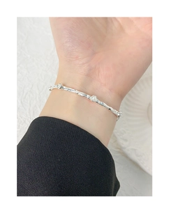Detail of silver S925 bracelet with wrinkled texture and three white pearls on model wrist