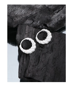 Gros plan de boucles d'oreilles créoles torsadées en argent sur fond de charbon noir