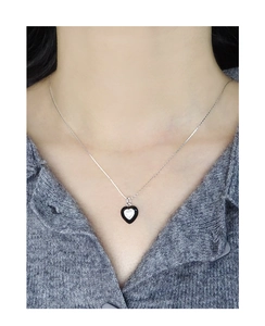 Detail of silver S925 heart pendant necklace with black enamel inlay on female model