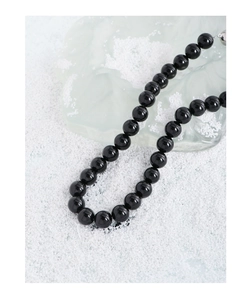 Détail macro de perles d'agate noire polies avec reflets et fermoir en métal brillant