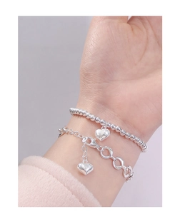 Detail of a 925 sterling silver heart charm bracelet set worn by a model on a wrist
