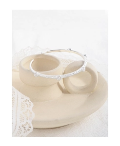Close-up of S925 sterling silver open bangle with hammered texture on a ceramic stand