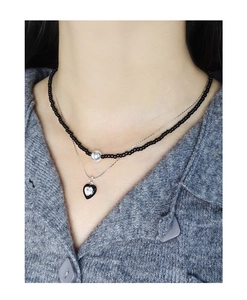 Close-up of double layer necklace featuring black beads and silver heart zircon pendant
