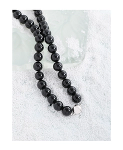 Macro des perles d'onyx noir poli et fermoir en argent de ce collier en argent S925