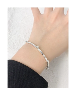 Detail of silver wavy textured bangle with three white pearls worn on a model's wrist