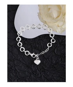 Macro view of S925 sterling silver chain bracelet with heart charm on black textured paper