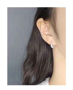 Détail de la boucle d'oreille créole en argent avec texture torsadée portée par un modèle