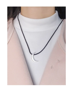 Detail of silver crescent moon pendant with adjustable black cord on a model
