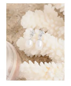 Macro shot of silver star studs with teardrop pearls on a coral decorative display