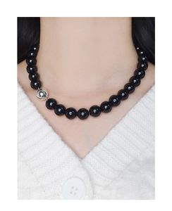 Détail du collier en argent S925 avec perles d'agate noire sur un pull blanc