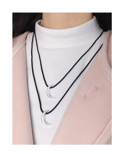 Close-up of double-layer moon pendant necklace with black cord on neck of a model