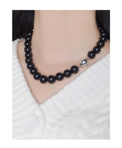 Détail d'un collier en argent S925 avec perles d'onyx noir sur fond de pull en maille blanc