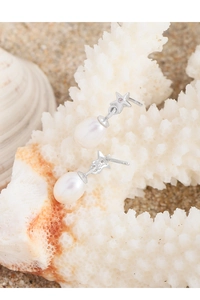 Detail of S925 sterling silver star stud earrings with teardrop natural pearls on coral
