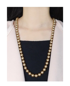 Detail shot of long champagne gold pearl necklace layering on a stylish woman outfit