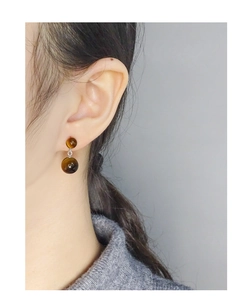 Détail de boucles d'oreilles double boules en œil de tigre avec texture naturelle brune