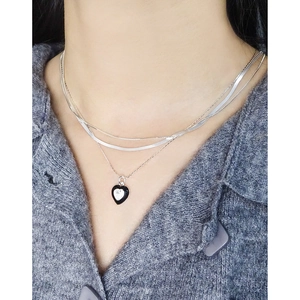 Three-layer silver necklace set with black heart zircon pendant on a female model