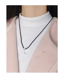 Close-up of a silver crescent moon pendant on an adjustable black cord necklace
