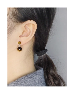 Détail de boucles d'oreilles rondes en œil de tigre avec clous en argent S925 sur modèle