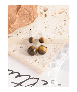 Vue détaillée des boucles d'oreilles en pierre d'oeil de tigre sur pierre texturée