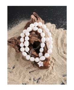 Détail de perles irrégulières et pendentif étoile de mer avec zircon sur bois flotté