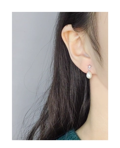 Macro shot of S925 silver star earring with white pearl drop on model ear