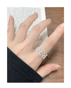 Detaillierte Nahaufnahme eines silbernen hohlen Blumenrings mit Zirkon auf einem Buch