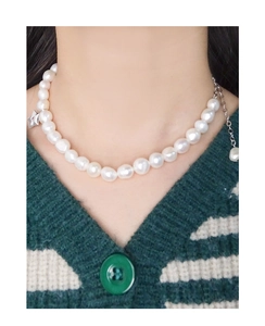 Détail du pendentif étoile de mer sur collier en perles porté sur un tricot