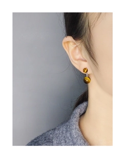 Gros plan d'un modèle portant des boucles d'oreilles en œil de tigre et argent S925