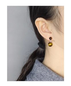 Gros plan de boucles d'oreilles double œil de tigre portées avec un pull doux