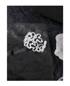 Nahaufnahme des silbernen hohlen Blumenrings mit Zirkonia auf schwarzer Basis