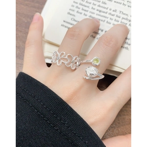 Set aus silbernem durchbrochenem Blumen-Zirkonia-Ring und Edelsteinring am Finger getragen