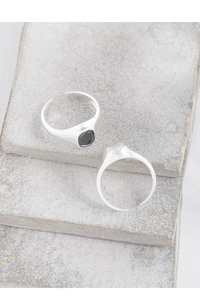 Close-up of minimalist silver open rings with square zircon stones on stone display