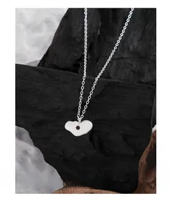 Gros plan du collier cœur en argent avec étoile noire sur un fond de charbon texturé