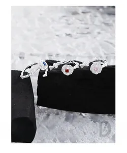 Detail of three S925 silver rings with rose flowers and colorful zircons on rocks