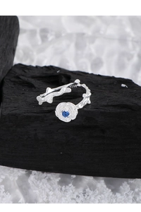Macro detail of S925 silver rose ring featuring withered branch texture and blue gemstone