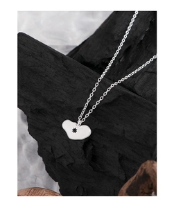 Détail d'un pendentif cœur en argent avec étoile noire sur un fond texturé sombre