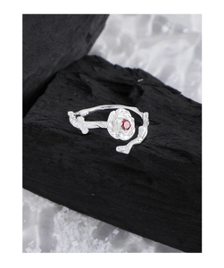Macro shot of silver rose ring featuring a red zircon and textured twig band